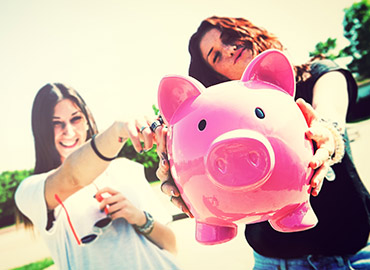 Young ladies holding out piggy bank.