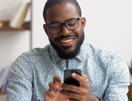 Smiling man looking at his savings account on his phone.