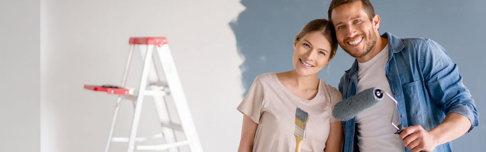 A happy couple painting a room in their home.