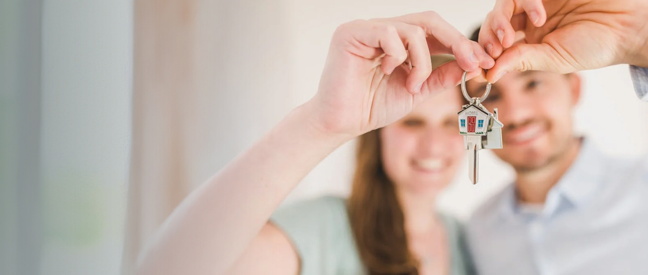 Happy young couple showing us their house key.