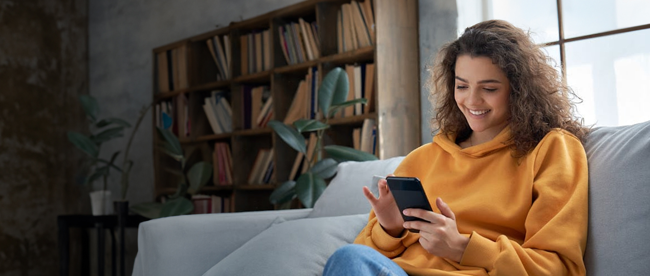 Girl on couch smiling while using her phone.